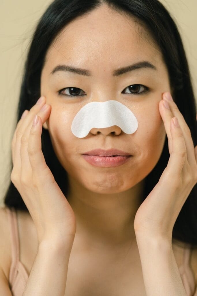 A woman using a nose strip for skincare routine